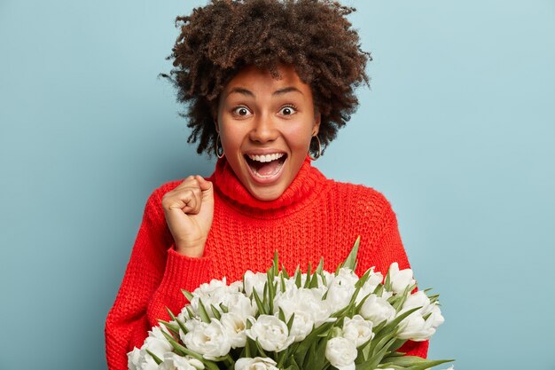 Young woman with curly hair holding bouquet of white flowers