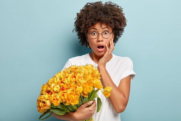 Young woman with curly hair holding bouquet of yellow flowers