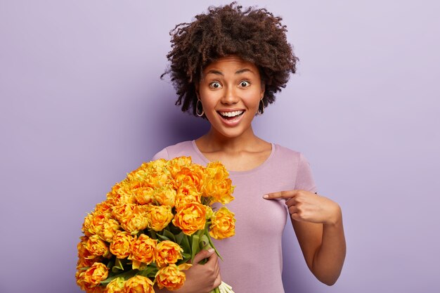 Young woman with curly hair holding bouquet of yellow flowers