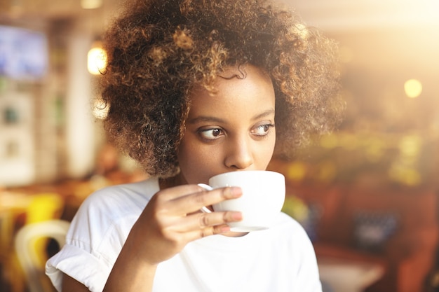 Free photo young woman with curly hair sitting in cafe