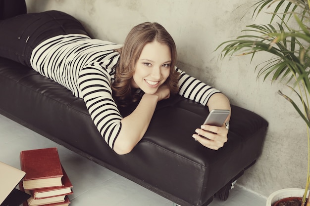 Free photo young woman with curly hair using her smartphone