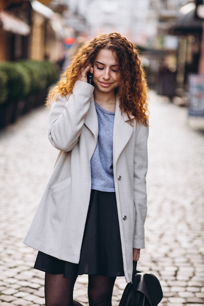 Young woman with curly hair using phone at the street