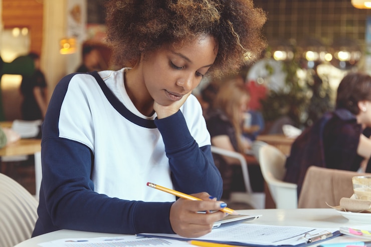 Free Photo young woman with curly hair using tablet in cafe