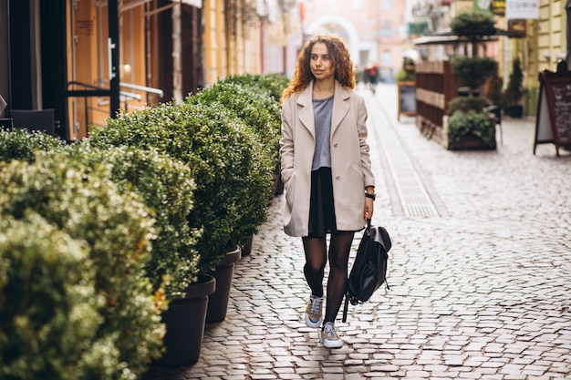 Young woman with curly hair walking at a cafe street