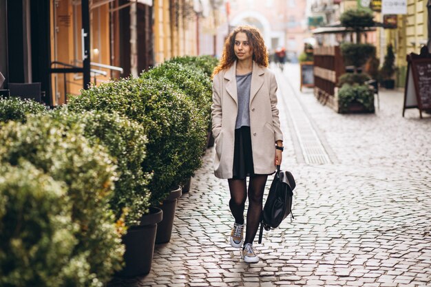 Молодая женщина с вьющимися волосами, прогулки на улице кафе