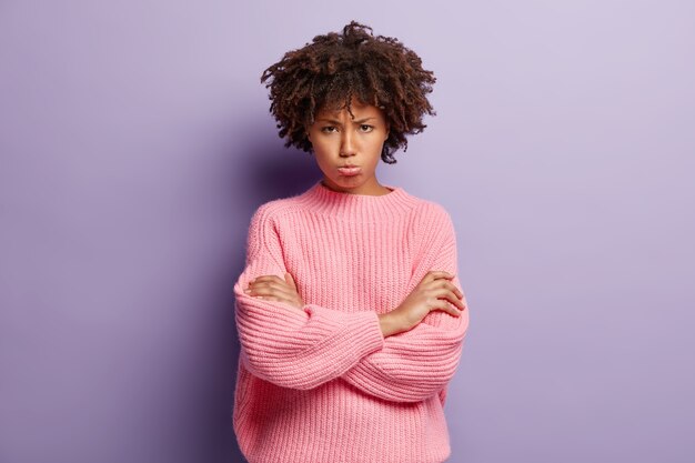 Young woman with curly hair wearing pink sweater