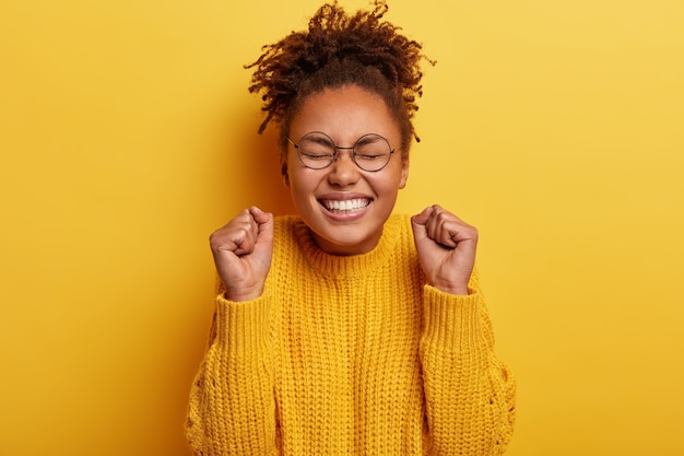 Foto gratuita giovane donna con i capelli ricci che indossa un maglione giallo