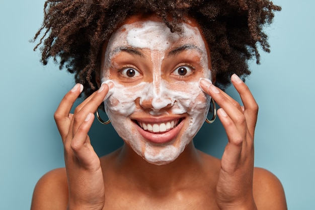 Giovane donna con capelli ricci con maschera facciale