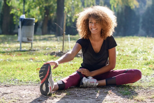 Free photo young woman with curly hair working out in the afternoon