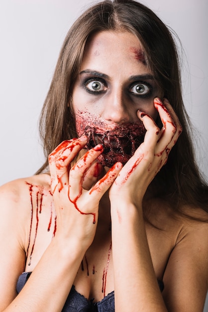 Young woman with damaged face and bloody hands