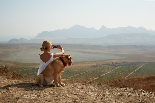 높은 산에 앉아 화창한 날에 강아지와 함께 젊은 여성