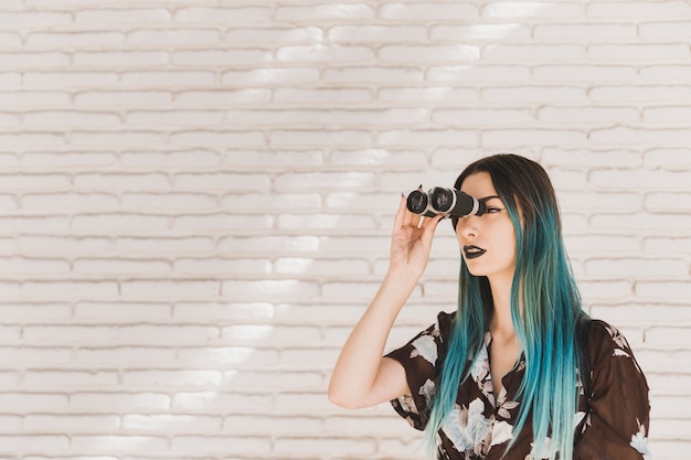 Young woman with dyed hair looking through binocular
