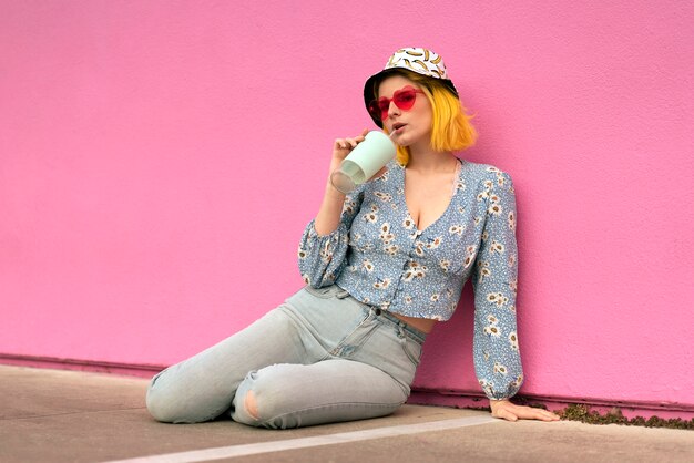 Young woman with dyed hair near pink wall