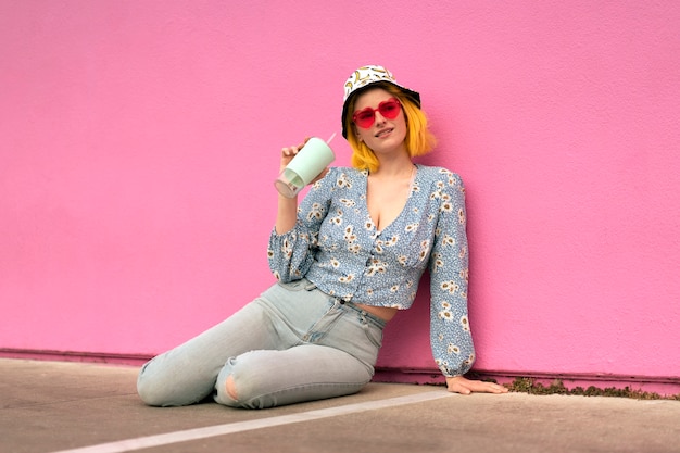 Giovane donna con i capelli tinti vicino al muro rosa