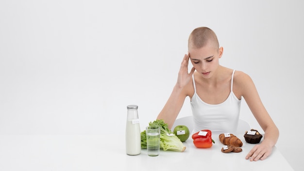 Foto gratuita giovane donna con un disturbo alimentare accanto al cibo con numeri di calorie