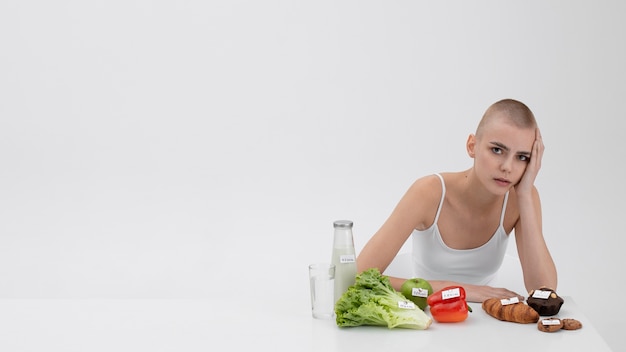 Free photo young woman with an eating disorder next to food with calories numbers