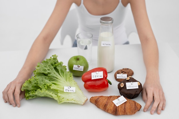 Free photo young woman with an eating disorder next to food with calories numbers