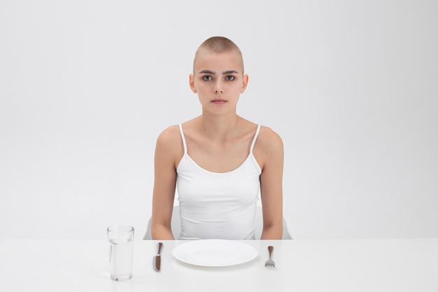 Молодая женщина с расстройством пищевого поведения сидит за столом