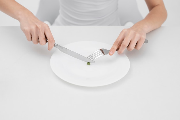 Young woman with an eating disorder wanting to eat a pea