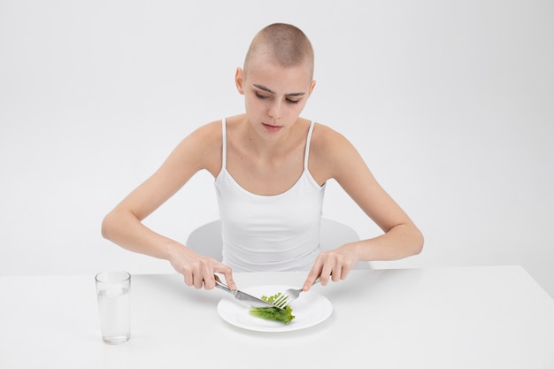 Foto gratuita giovane donna con un disturbo alimentare che vuole mangiare un po' di lattuga