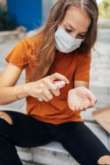 Foto gratuita giovane donna con maschera facciale disinfettando le sue mani