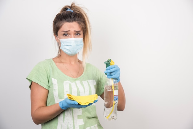 Young woman with facemask and supplies looking tired.