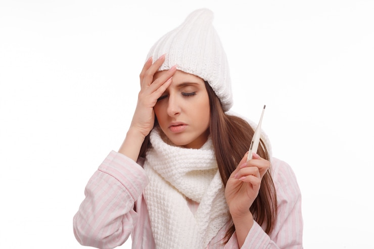 Free Photo young woman with fever and holding a thermometer