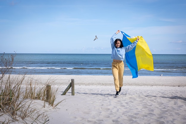 바다 배경에 우크라이나 국기를 든 젊은 여성