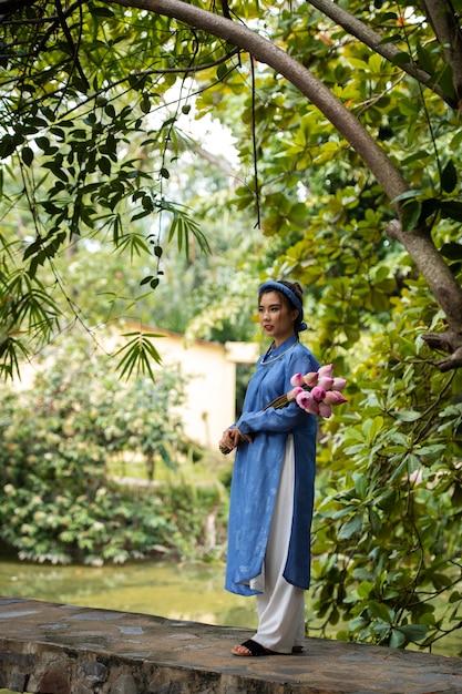 アオザイの衣装を着た花の花束を持つ若い女性