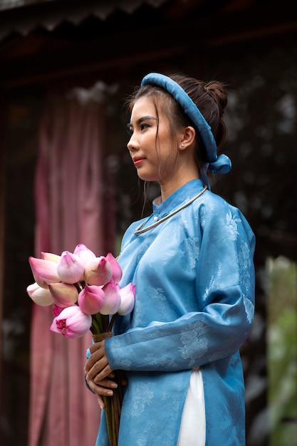 Giovane donna con bouquet di fiori che indossa un costume ao dai