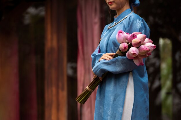 アオザイの衣装を着た花の花束を持つ若い女性