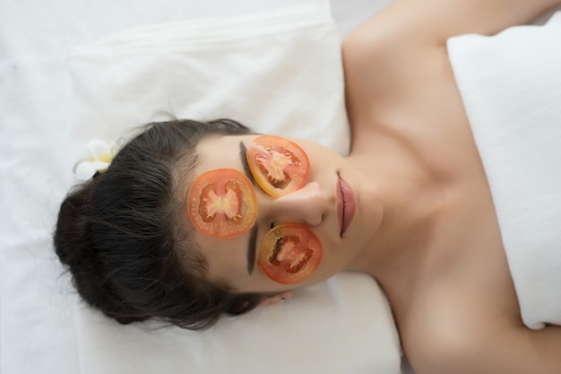 Young woman with fresh tomatoes mask in spa.