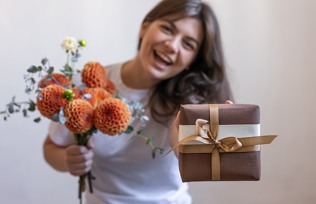 Young woman with a gift box and a bouquet of chrysanthemum flowers