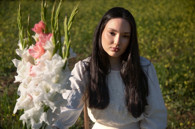 Young woman with gladiolus in nature