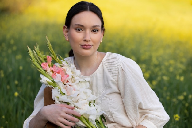 Young woman with gladiolus in nature