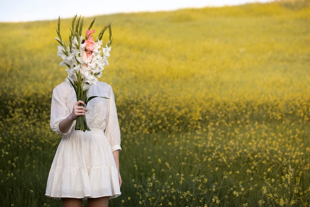 Foto gratuita giovane donna con gladiolo in natura