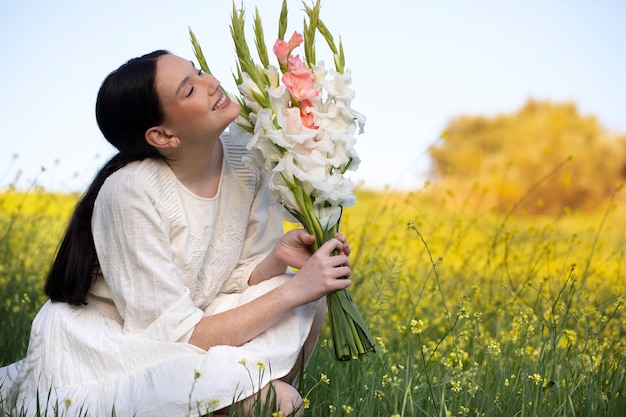 Young woman with gladiolus in nature