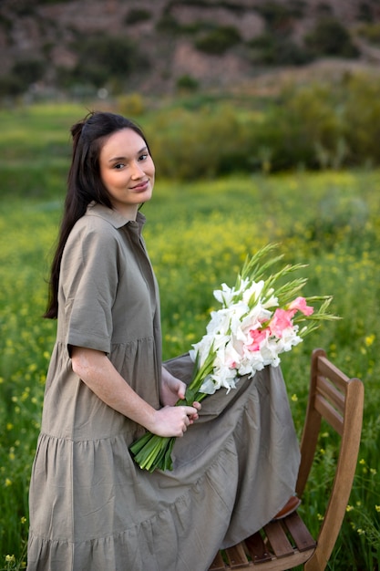 Молодая женщина с гладиолусами на природе