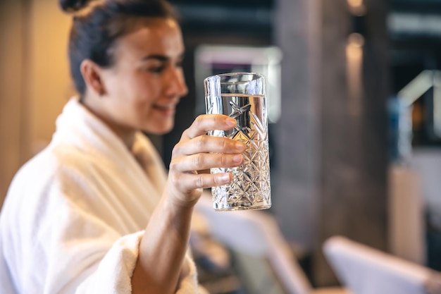 Una giovane donna con un bicchiere d'acqua dopo la sauna sta riposando