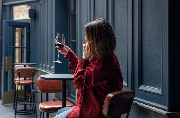 A young woman with a glass of wine on the terrace of a restaurant