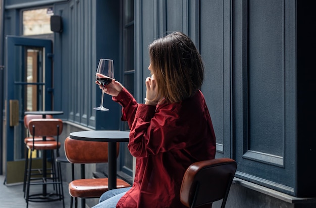 레스토랑 테라스에서 와인 한 잔을 들고 있는 젊은 여성