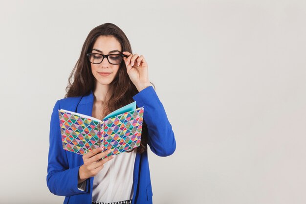 Young woman with glasses holding a colorful notebook