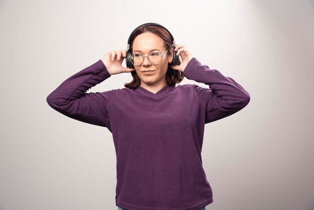 Young woman with glasses listening music in headphones on a white. High quality photo