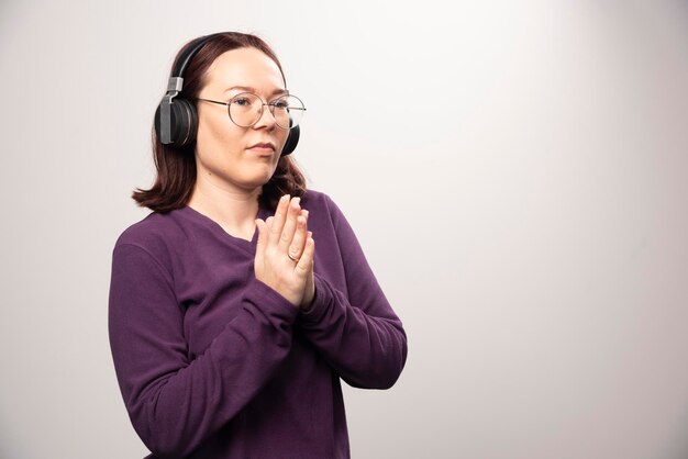 Молодая женщина в очках, слушая музыку в наушниках на белом. Фото высокого качества