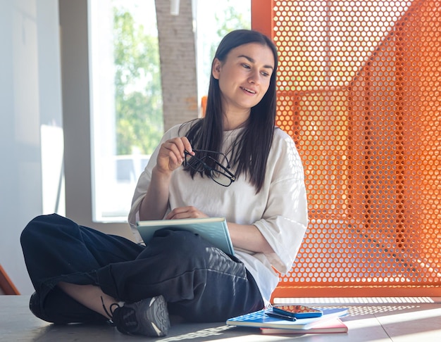 Young woman with glasses and notebook in modern interior study concept