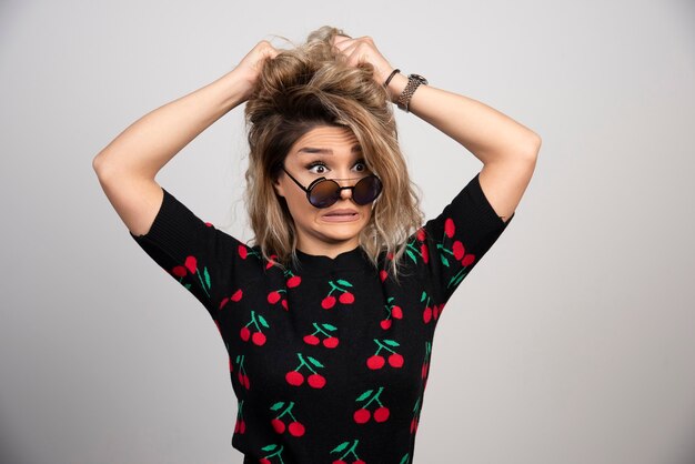 Free photo young woman with glasses standing on gray wall.