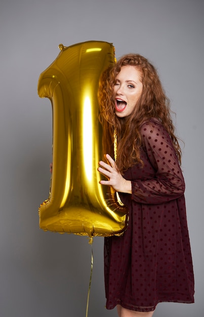 Молодая женщина с золотым воздушным шаром празднует первый день рождения своей компании
