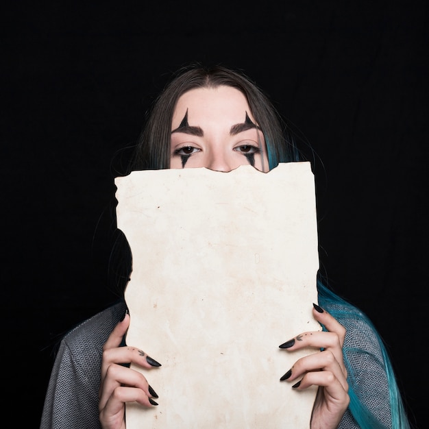 Free photo young woman with halloween makeup holding piece of paper