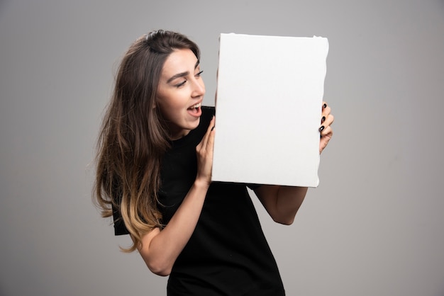 Free photo young woman with happy epression holding canvas.