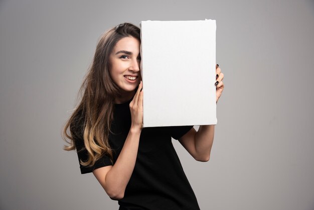 Young woman with happy expression holding canvas. 